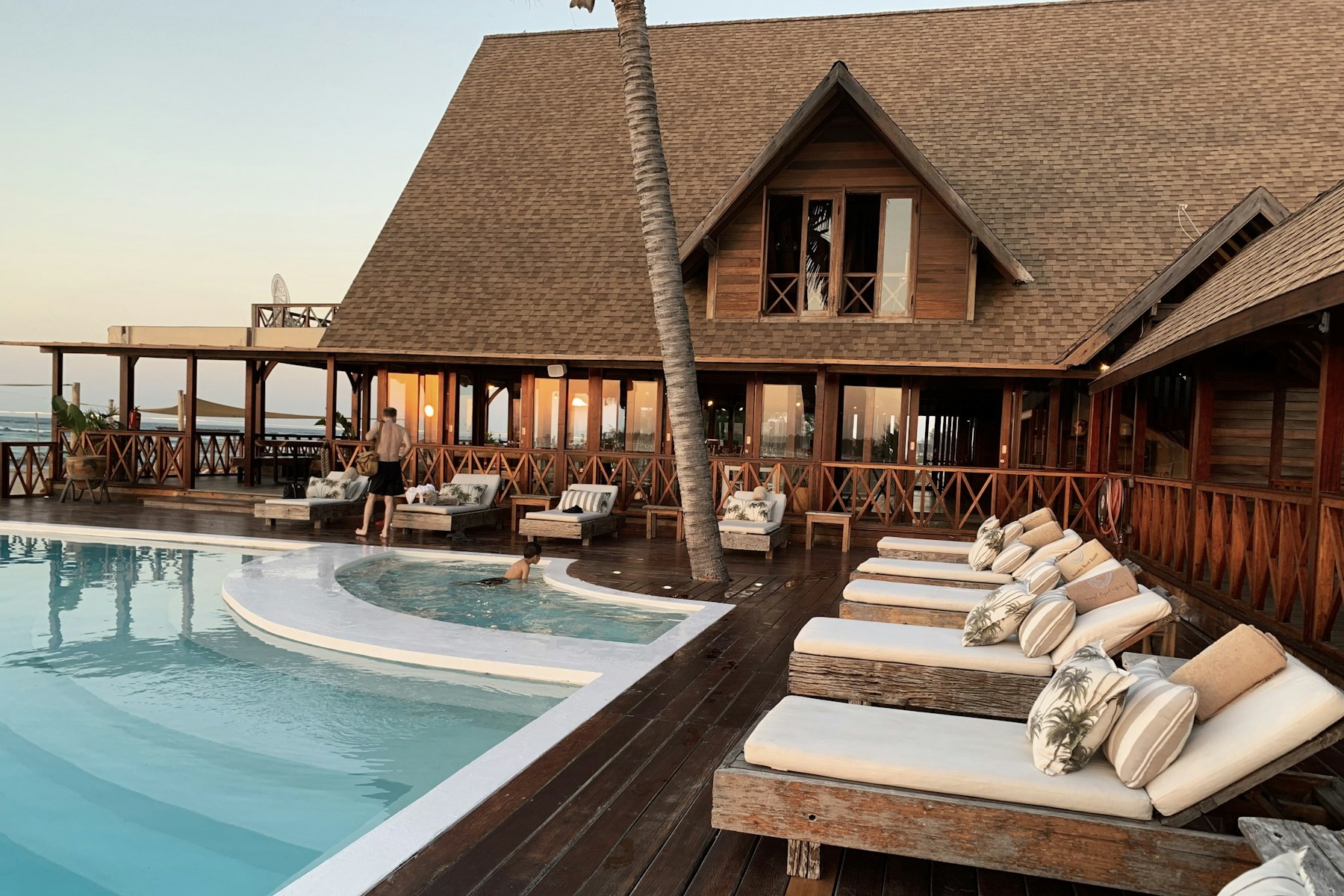 A resort pool with loungers and open-air hospitality spaces