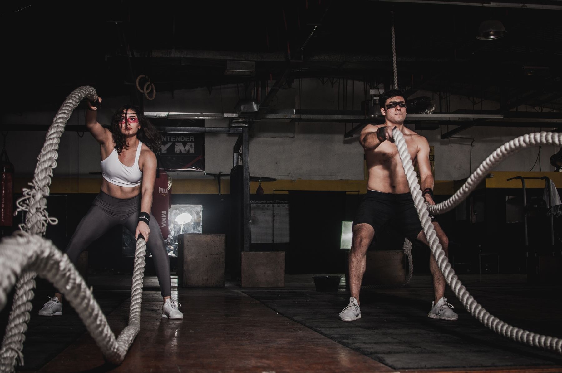 Two adults training with ropes in a gym